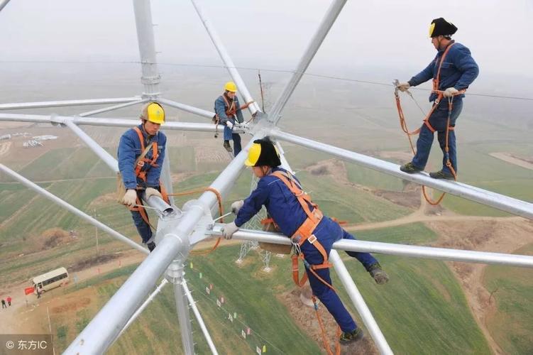 图为在安徽省明光市桥头镇,几名电力施工人员在110多米高空安装特高压