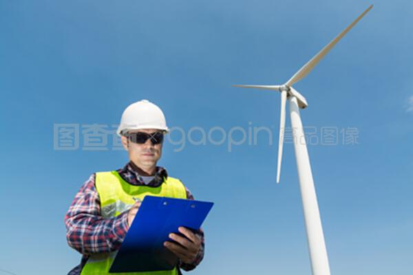 电动工程师用风力涡轮机在剪贴板上写报告
